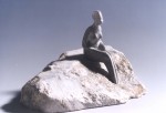 Femme assise sur un rocher.